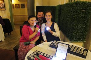 man kneeling next to two women with glowing rings