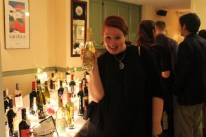 woman smiles like a goof while holding bottle of white wine