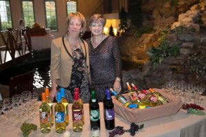 two women standing with various colored wine bottles