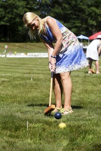 woman smacks her blue croquet ball with mallet at 4th annual croquet on the green