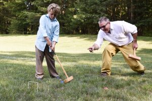 man giving pointers to young boy on croquet yard