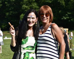 woman with face paint smiles with woman in striped dress