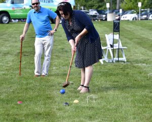 woman in polka dot dress hits blue croquet ball