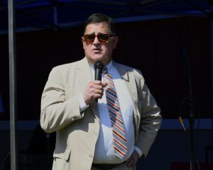 man in sunglasses and tan suit speaking into microphone at 4th annual croquet on the green
