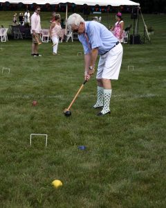 man in shorts and high socks hits black croquet ball