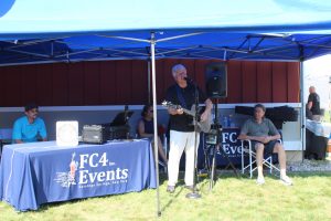 man plays guitar while singing under FC4 Events tents