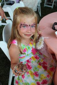 little girl eating chocolate ice cream with face paint