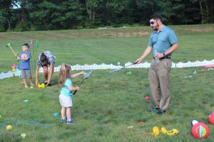 man teaching little girl badminton skills in kids zone