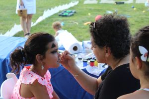 woman putting the finishing touches on a cat face paint