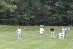 group playing croquet while man points at his shot