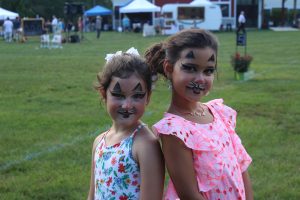 two little girls show off their cat face paint to camera