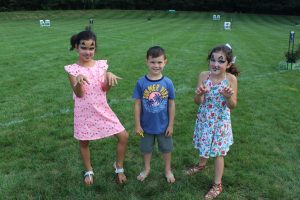 three children smiling for camera with croquet field in background