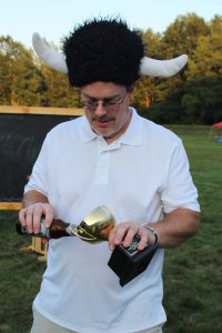 man in black fuzzy viking hat pours a celebratory beer in trophy cup