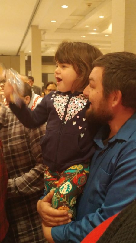Little girl smiling with dad at Holiday Tea party