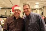 Man in Santa hat smiling with another man at the Holiday Tea event