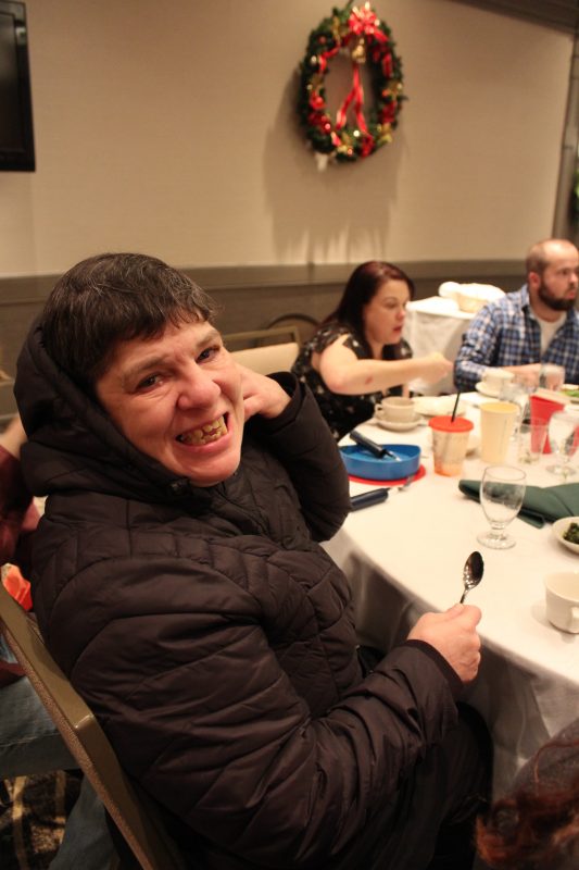 Woman sitting at table smiling at the Holiday Tea