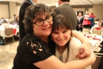 Two woman hugging and smiling at the Holiday Tea event