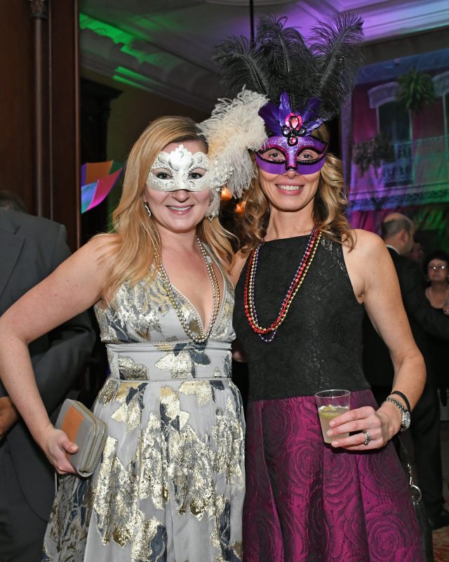 Two woman in dresses with matching mardi gras masks at Mardi Gras for AIM Services
