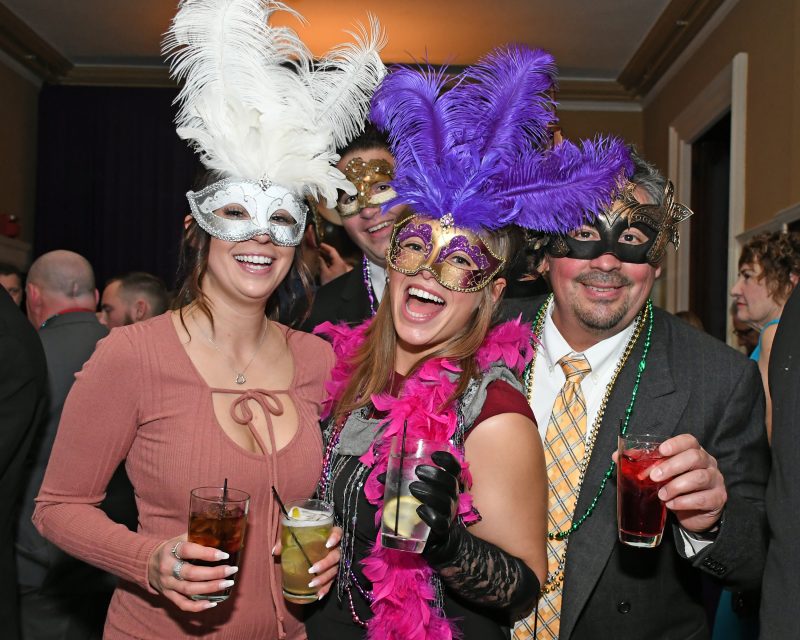Group of four people in mardi gras masks with feathers at Mardi Gras for AIM Services