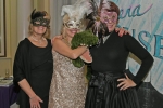 Three woman with mardi gras masks on and a stuffed crocodile at Mardi Gras for AIM Services
