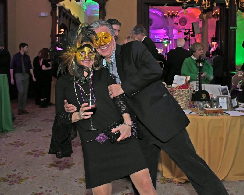 Couple laughing in yellow masks at Mardi Gras for AIM Services event