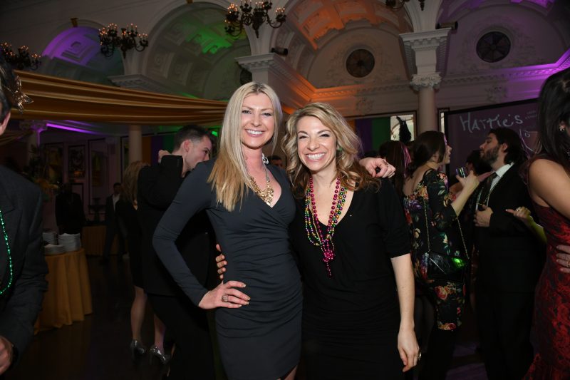 Two women smiling on dance floor at Mardi Gras event for AIM Services