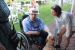 Man in wheelchair petting dog at the Saratoga Dog & Pony Show to benefit AIM Services, Inc.