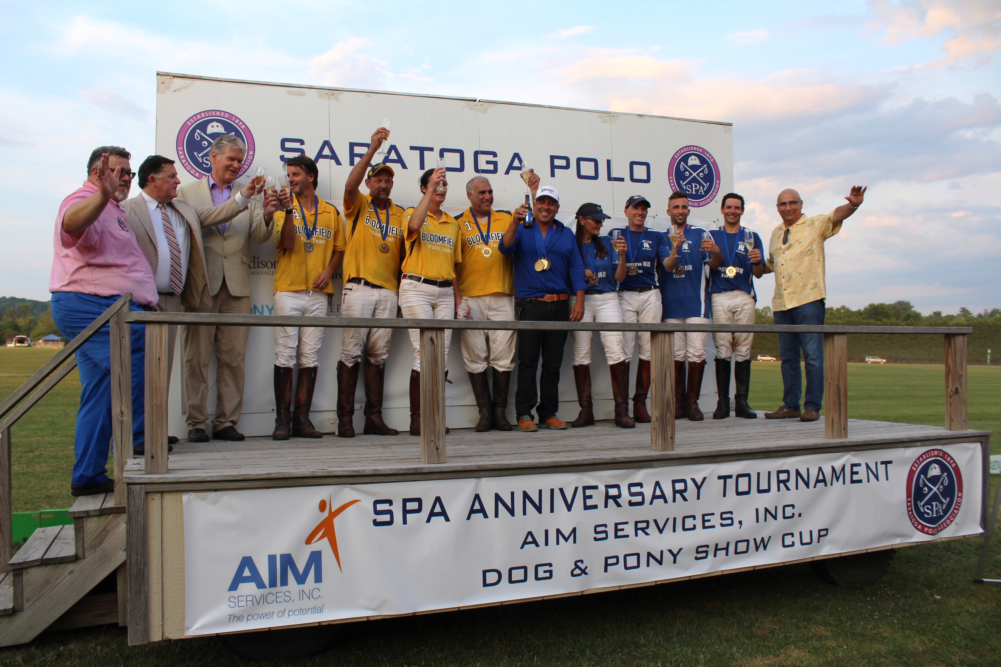 Polo teams on stage cheersing at the Saratoga Dog & Pony Show to benefit AIM Services, Inc.