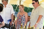 Two people smiling over a table of wine bottles at AIM services croquet on the green event