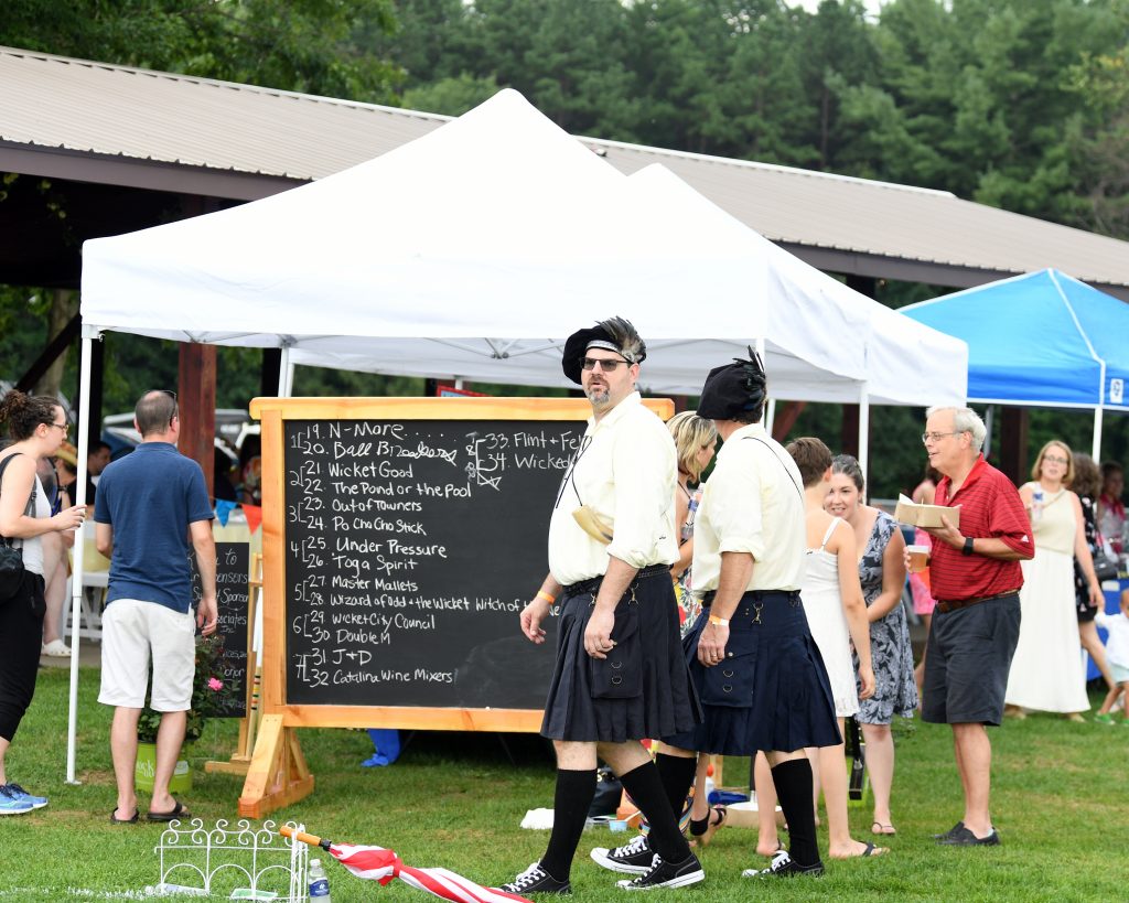 Group of people having a good time in front of the score board for Croquet at AIM Services Croquet on the Green event