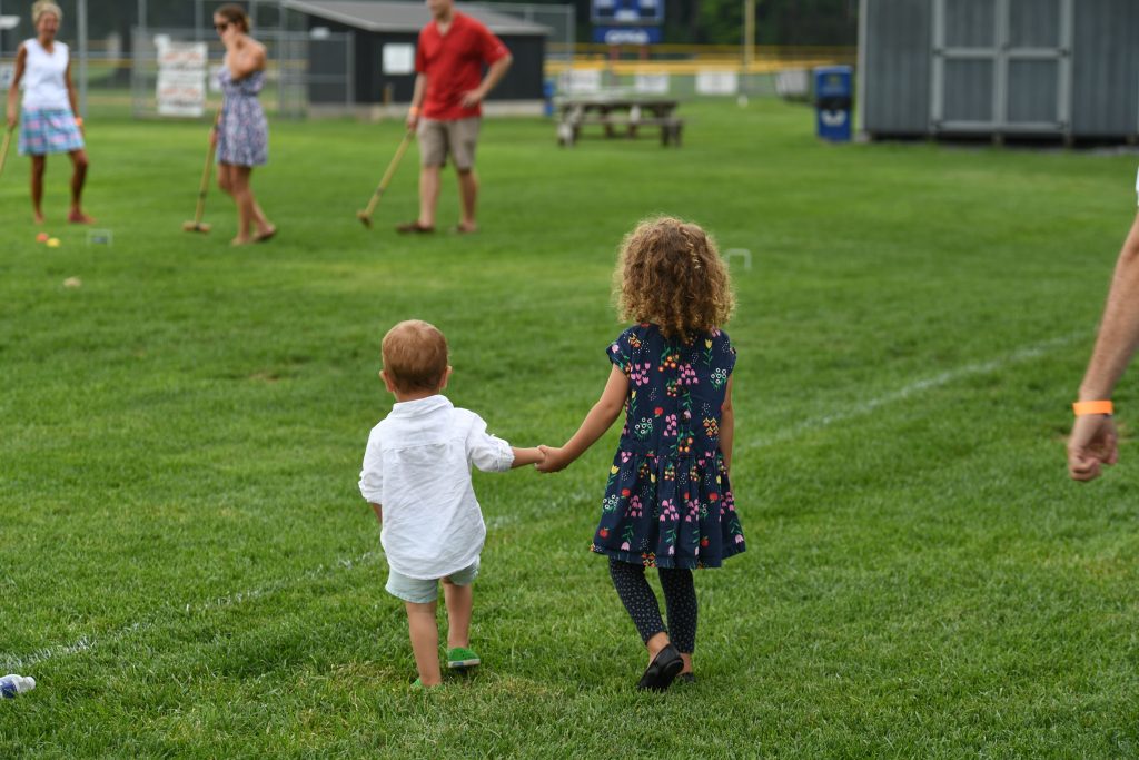 Two children walking hand in hand at AIM Services Croquet on the Green event