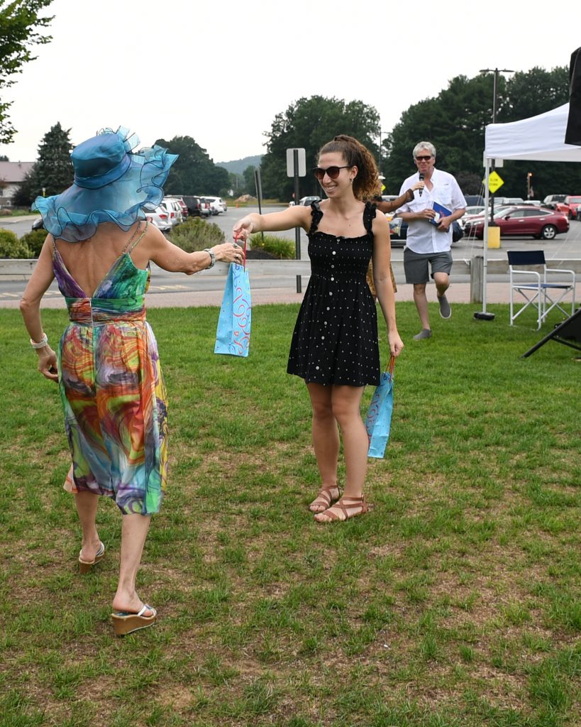 Woman handing off prize for best hat at AIM Services Croquet on the Green event