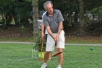 Man with cigar in his mouth taking a shot at AIM Services Croquet on the Green event