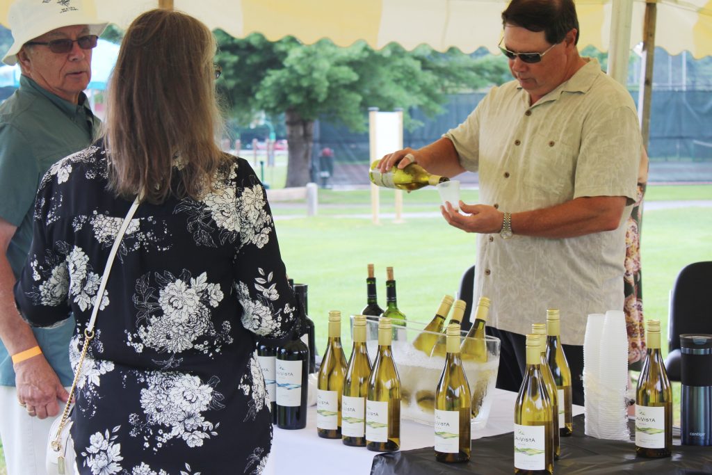 Brian Gwynn of specialty wines and more pouring wine at AIM Services Croquet on the Green event