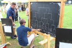 Tournament Judge writing fields on chalk board score board at AIM Services Croquet on the Green event