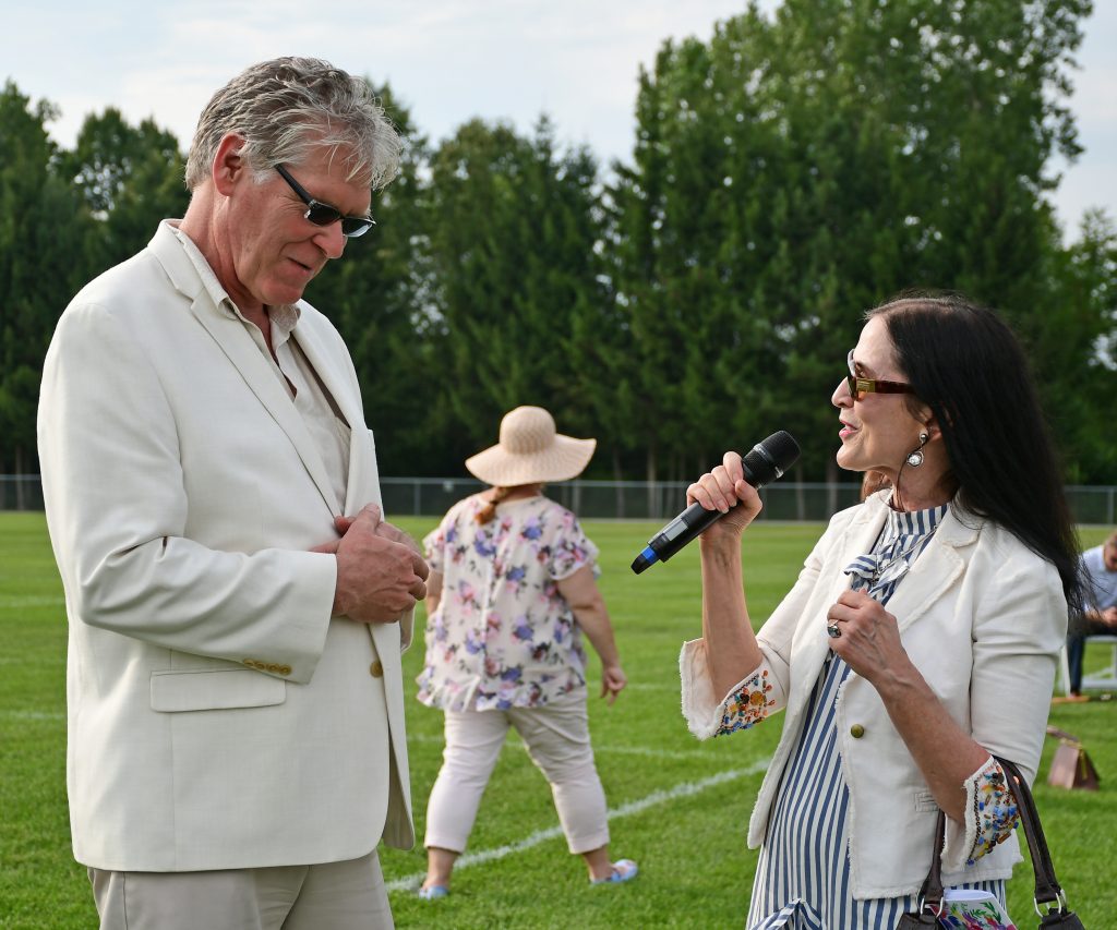Natalie Sillery speaking into a microphone looking at Walt Adams at Croquet on the Green 2019