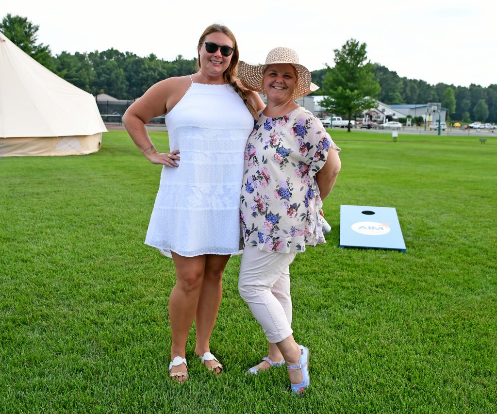 Two woman standing together with cornhole set in the background at Croquet on the Green 2019
