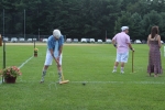 Man in bright plaid shirt with knee high socks with birds on them hitting a croquet ball with a mallet at Croquet on the Green 2019