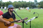 Side shot of Thomas Powers singing and playing guitar at Croquet on the Green 2019