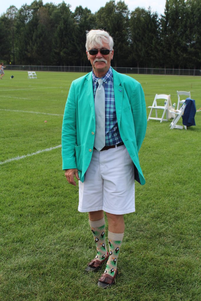 Man in bright colored aqua jacket with knee high socks with birds on them at Croquet on the Green 2019