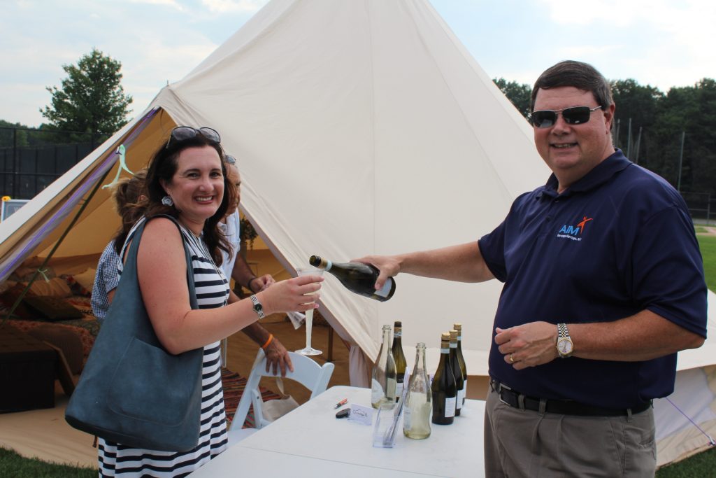 Brian Gwynn of Specialty Wines and More pouring sparkling wine for a woman