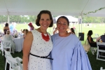 Woman in a white dress and red beaded necklace smiling with a woman in a blue blouse at Croquet on the Green 2019