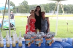 Group of three womens standing in front of table with vodka on it at Croquet on the Green 2019