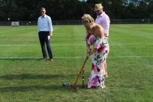 women in pink and white floral maxi dress lining up a croquet shot