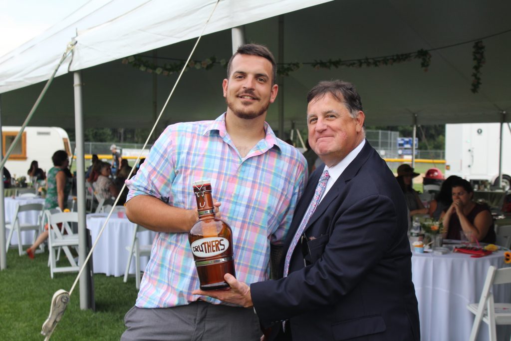 Matt Stevens, winner of Druthers beer for a year, holding a growler and posing with Executive Director Chris Lyons at Croquet on the Green 2019