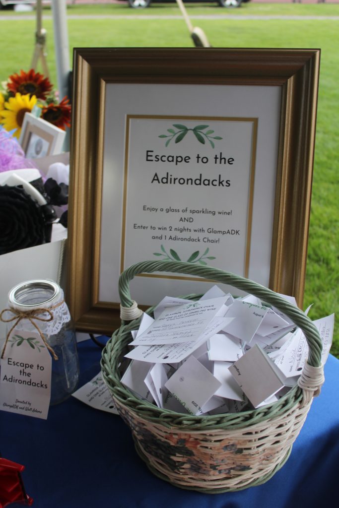 Sign for Escape the the Adirondacks package with a basket in front filled with entries to win the package at Croquet on the Green 2019