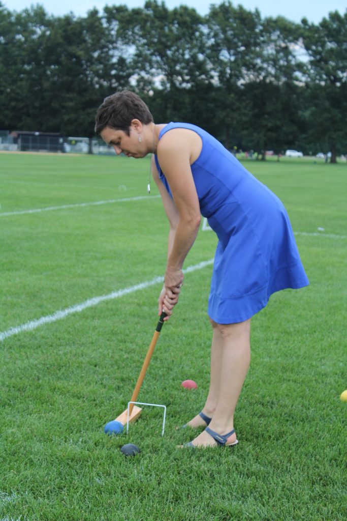 Woman in a blue dress taking a shot at croquet at Croquet on the Green 2019