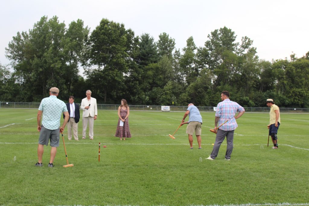 Man hitting croquet ball long distance as group of people look on at Croquet on the Green 2019