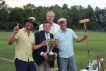 Winners of croquet, Brett and Brett Jr. Armstrong, holding trophy, mallet, and one finger up, with Chris Lyons and Walt Adams at Croquet on the Green 2019