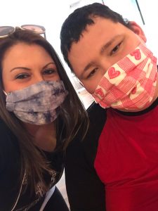Girl with tie-dye face mask posing with man with checkered hearts face mask